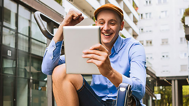 young man sitting outside looking at a tablet