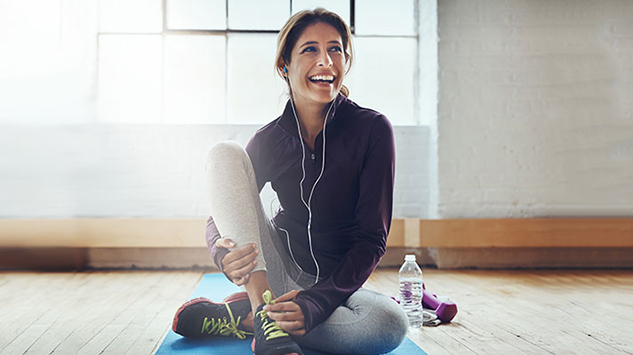 woman with headphones sitting on a yoga mat