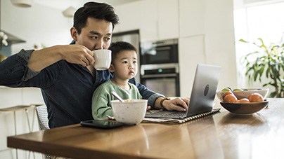 father working from home with young son on his lap