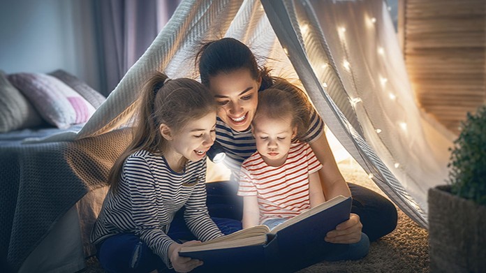 mom reading to two young daughters 